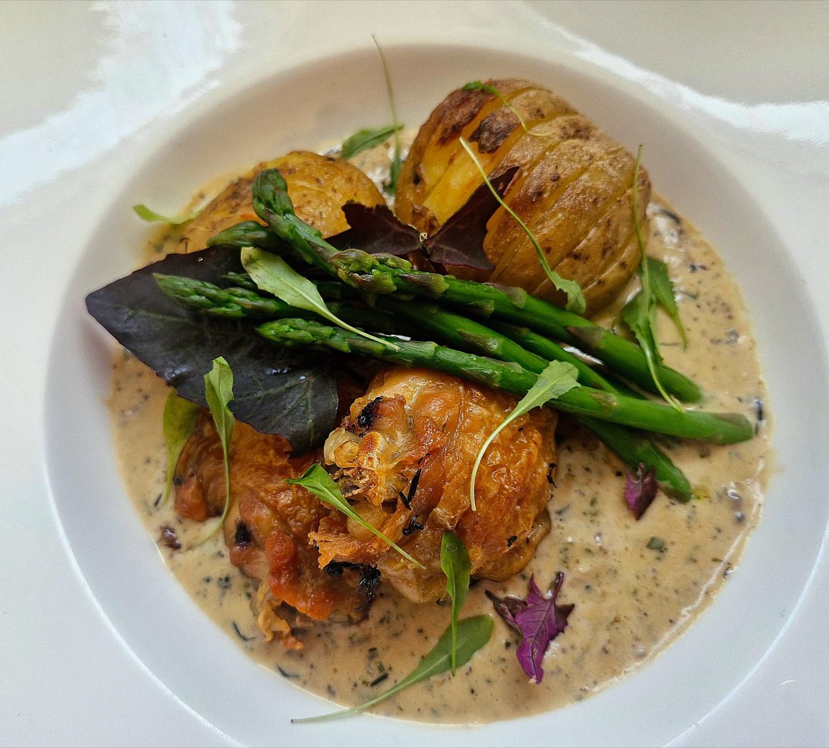 Roast chicken with hasselback potatoes, asparagus and a creamy herb sauce