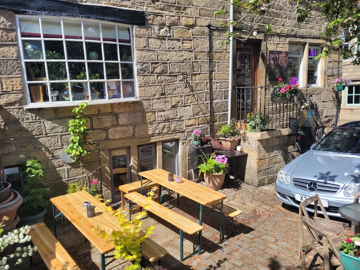 Sunny cobbled courtyard with wooden benches and flower pots outside the front door