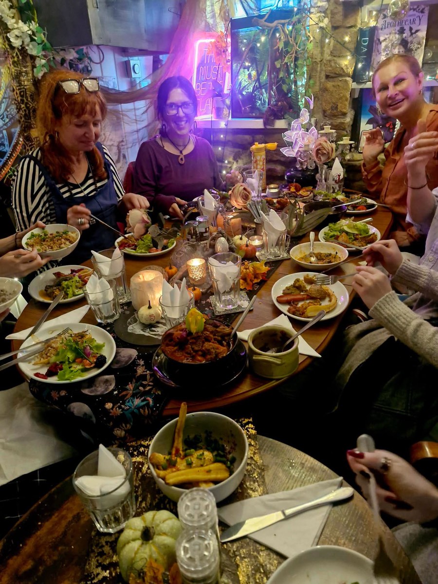 A round table laid with shared dishes, candles and mini pumpkins