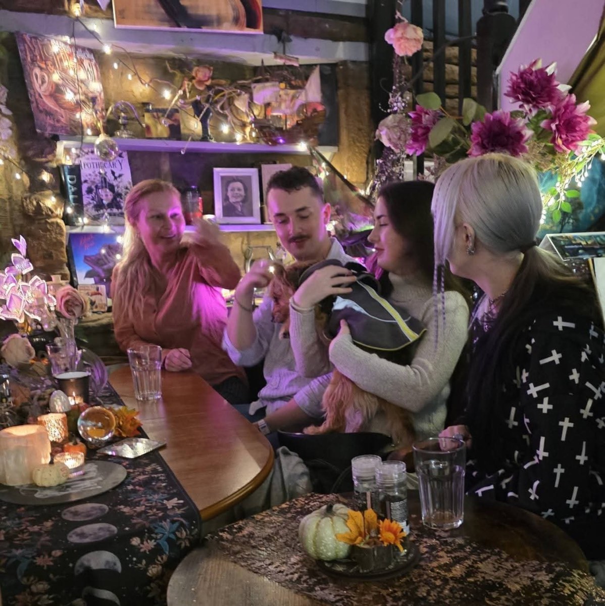 Friends cuddling a small dog at a candlelit table