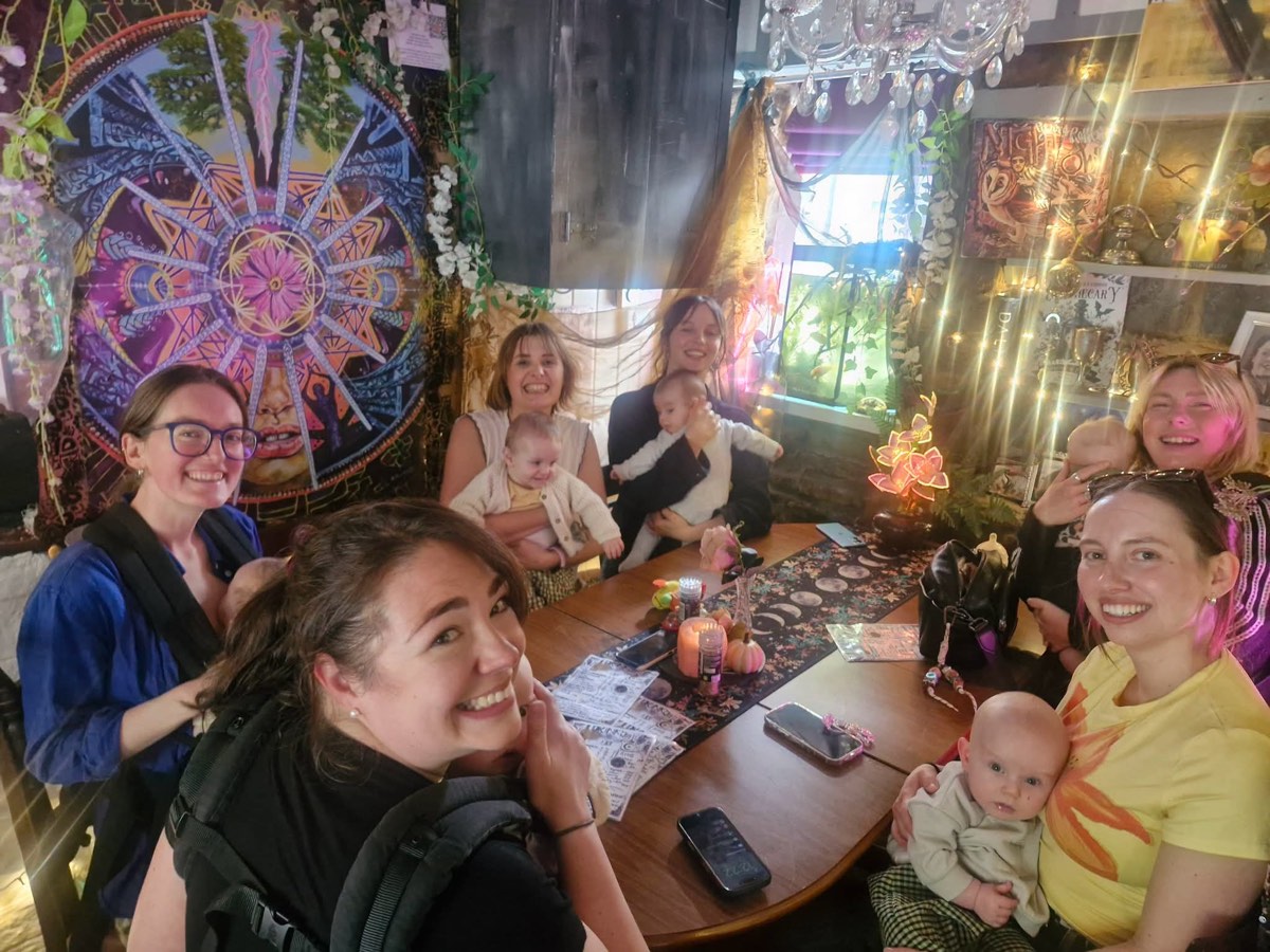 A parent and baby group smiling round a table